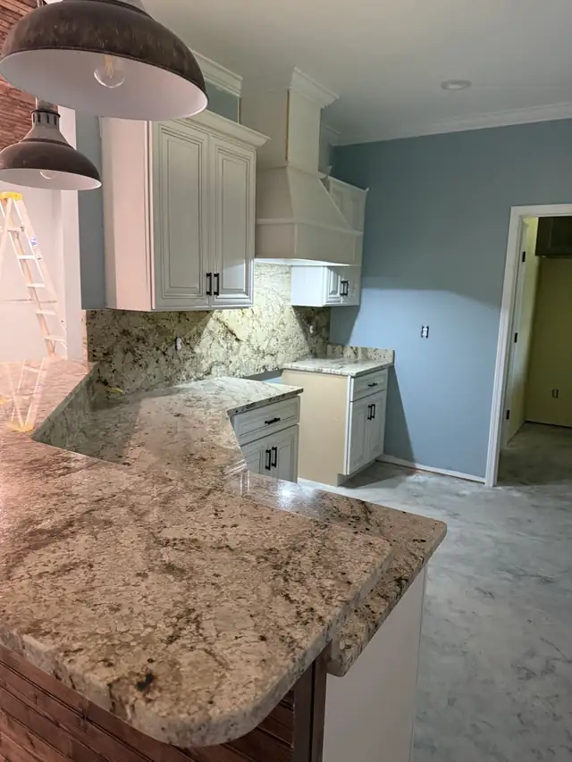 Brown and cream granite countertop with a full stone backsplash on white cabinets