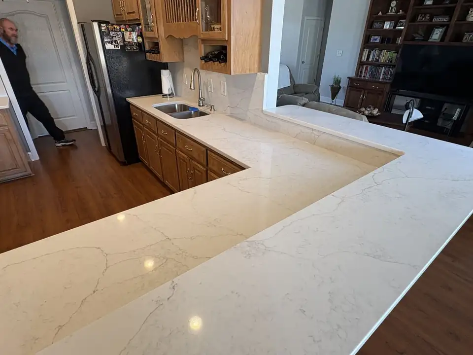 Long L-shaped white stone countertop over light wood cabinets, one of the stone countertops by Raccoon Stone & Tile Works in Byron, GA