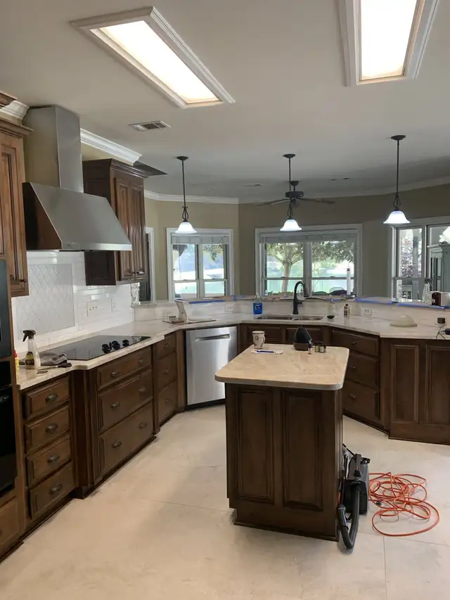 Kitchen with dark stained cabinets, a stone-topped island, light stone countertops and a white tile backsplash